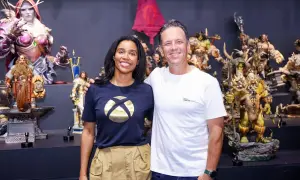 Phil Spencer y una colega posan sonrientes entre figuras de fantasía, incluyendo orcos y elfos.