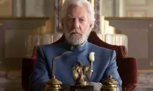 President Snow, con su barba blanca y traje azul, planea los Juegos del Hambre desde su trono.