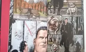 Los chicos en un parque otoñal, uno sentado en un banco con un bulldog, otro de pie con un perro.