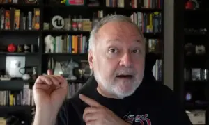 Tim Cain, con estanterías llenas de libros y objetos, habla con entusiasmo.