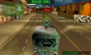 Vehículo con cara de payaso en una carrera de "Road Kill", rodeado de edificios y metal retorcido.
