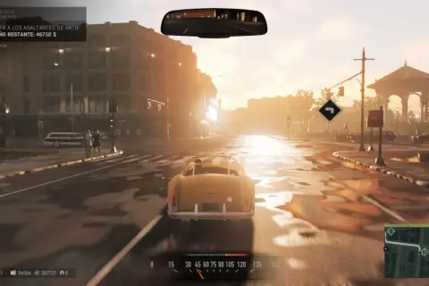Conduciendo un coche clásico en una calle mojada, con el sol del atardecer iluminando la ciudad. El objetivo actual en Mafia 3 es eliminar a los asaltantes de Artie.