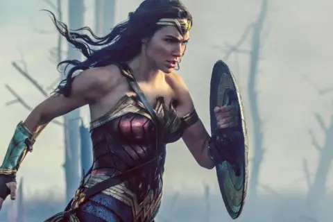 La heroína con el nombre de Wonder Woman, con su armadura icónica y escudo, se prepara para la batalla en un paisaje desolado.