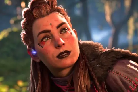 Aloy, la heroína de Horizon, mira al cielo con determinación. Su rostro está adornado con marcas tribales y su cabello recogido en un peinado elaborado.