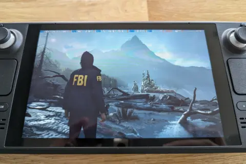 Alan Wake 2 en Steam Deck, con un personaje con chaqueta del FBI en un paisaje nevado y montañoso.