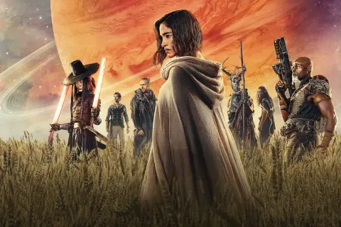 Un grupo de guerreros, incluyendo a una mujer con capa y espadas de luz, se alza en un campo de trigo bajo un cielo anaranjado y un planeta gigante. Son los rebeldes de Rebel Moon.