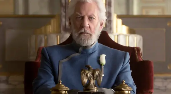 President Snow, con su barba blanca y traje azul, planea los Juegos del Hambre desde su trono.