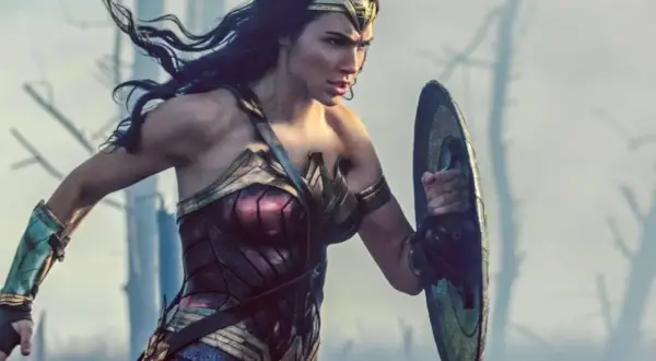 La heroína con el nombre de Wonder Woman, con su armadura icónica y escudo, se prepara para la batalla en un paisaje desolado.