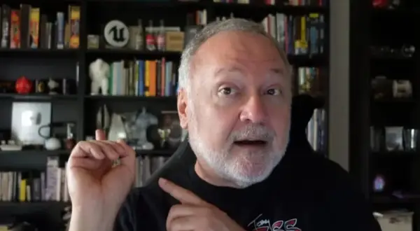 Tim Cain, con estanterías llenas de libros y objetos, habla con entusiasmo.