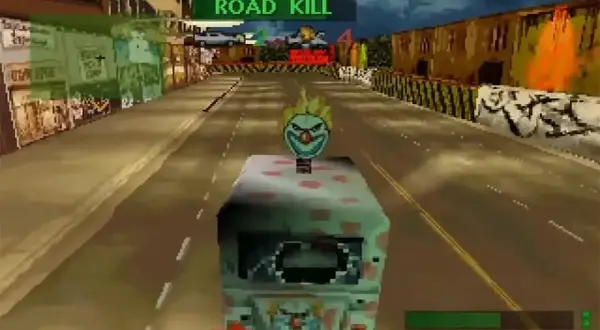 Vehículo con cara de payaso en una carrera de "Road Kill", rodeado de edificios y metal retorcido.