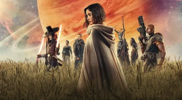 Un grupo de guerreros, incluyendo a una mujer con capa y espadas de luz, se alza en un campo de trigo bajo un cielo anaranjado y un planeta gigante. Son los rebeldes de Rebel Moon.