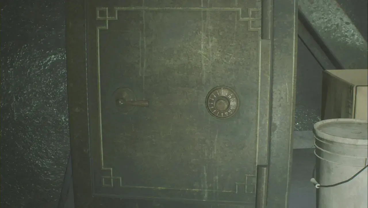 Caja fuerte verde con dial numérico y palanca, junto a un cubo blanco.