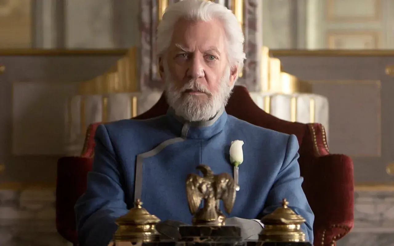 President Snow, con su barba blanca y traje azul, planea los Juegos del Hambre desde su trono.
