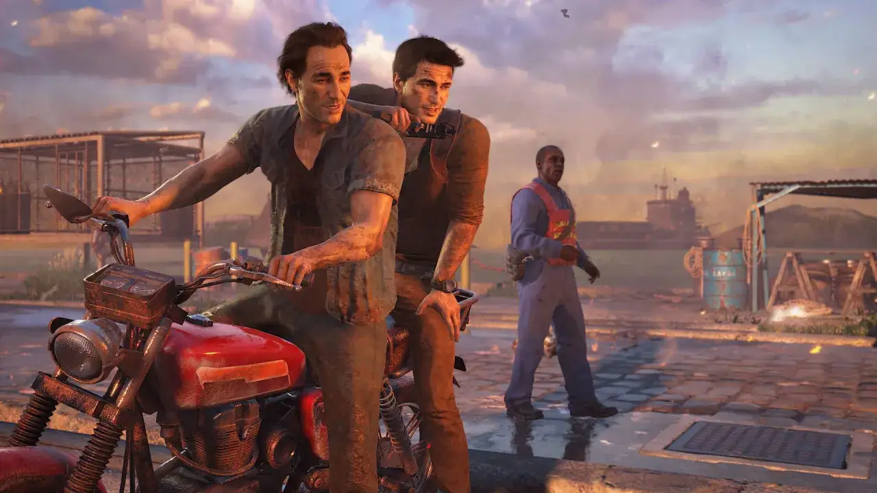 Nathan Drake y Sully en una moto roja, listos para otra aventura de la saga Uncharted. Un hombre con chaleco naranja los observa.