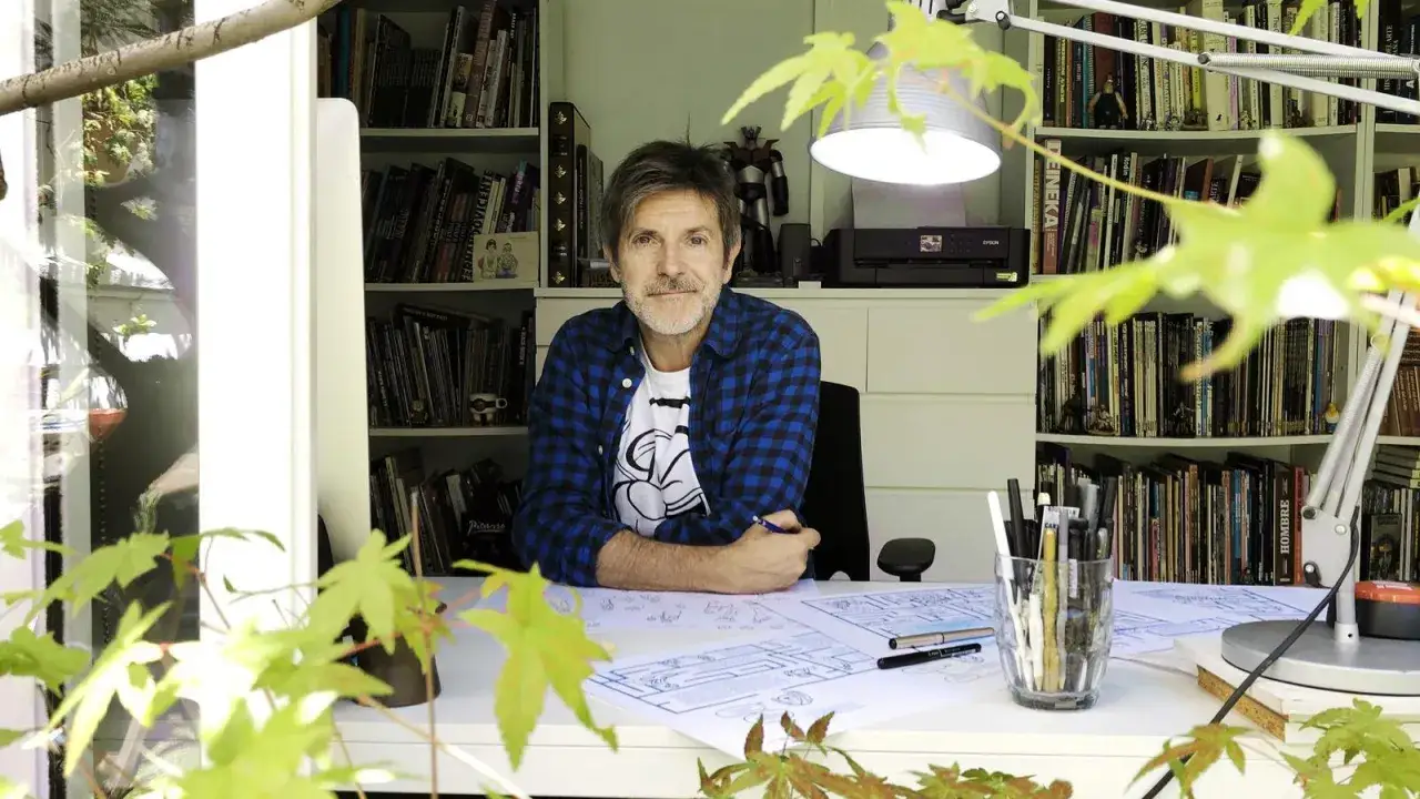 Paco Roca, rodeado de sus libros y bocetos, sonríe mientras trabaja en su estudio.