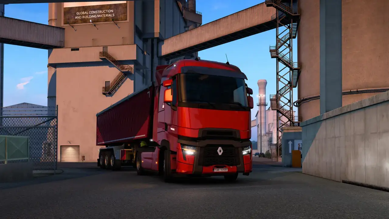 Cami&oacute;n rojo en Euro Truck Simulator 2 PS5, listo para entregar materiales de construcci&oacute;n en una planta industrial.