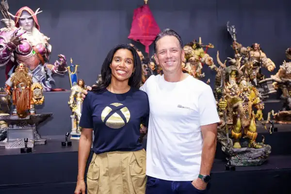 Phil Spencer y una colega posan sonrientes entre figuras de fantasía, incluyendo orcos y elfos.