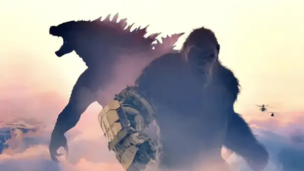 Kong con su guantelete mecánico y Godzilla emergen de las nubes, listos para la batalla en Godzilla y Kong: El Nuevo Imperio. Helicópteros sobrevuelan.