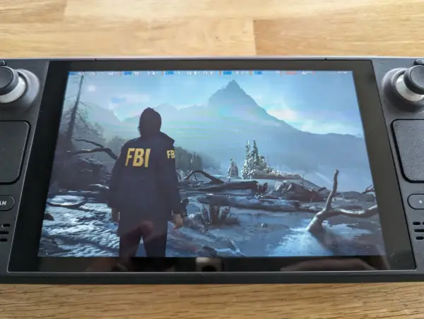 Alan Wake 2 en Steam Deck, con un personaje con chaqueta del FBI en un paisaje nevado y montañoso.